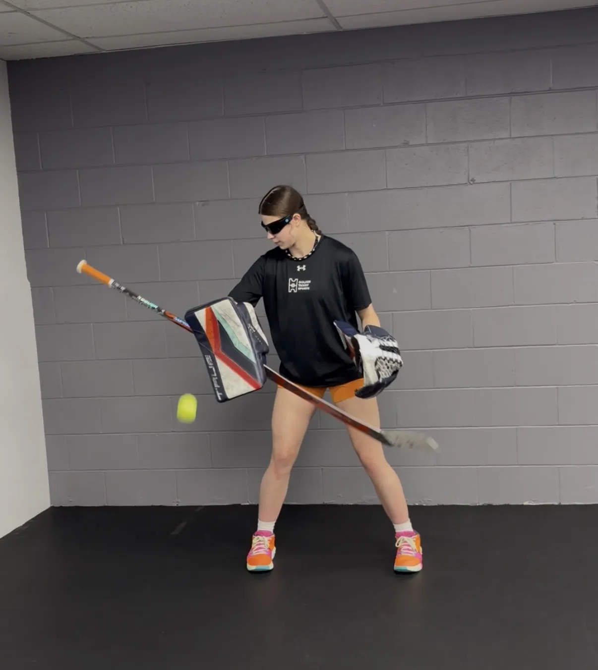 A goaltender in strobe glasses tracking a tennis ball during a reaction drill