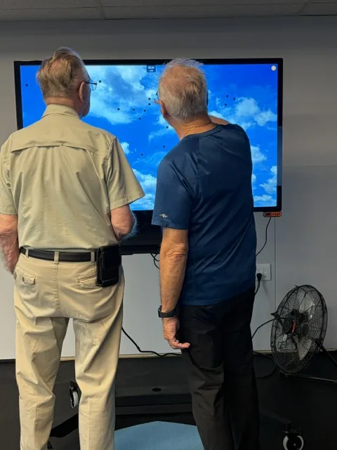 Two men doing a visual tracking exercise on a large training screen